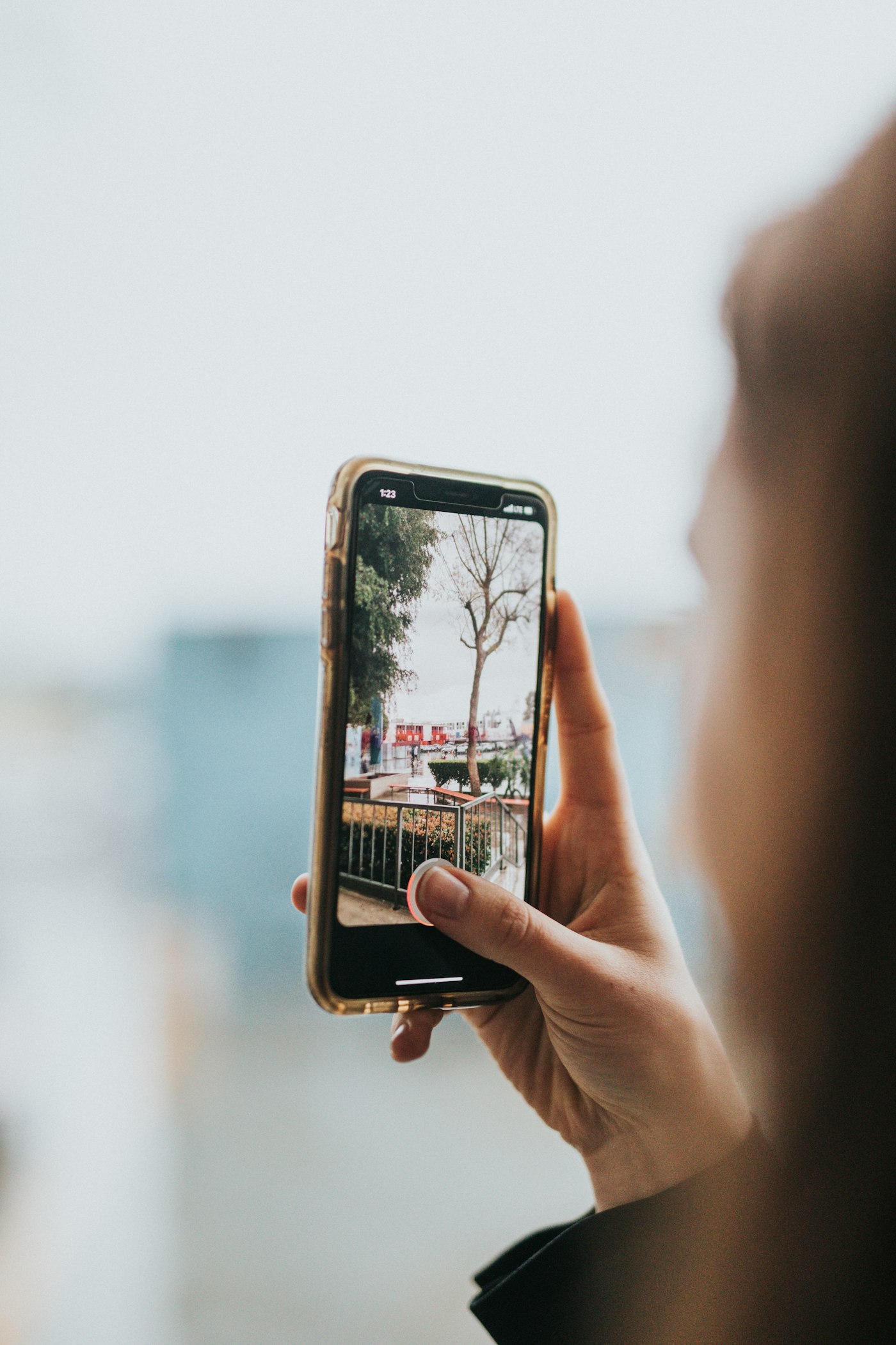 Hand holding a smartphone capturing a photo outdoors