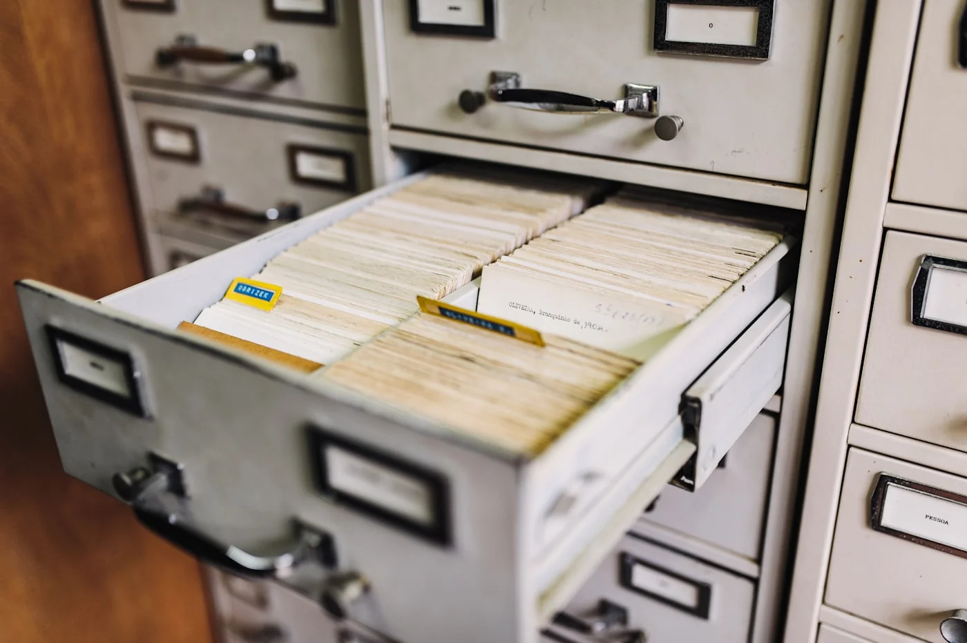 A row of metal file cabinet drawers filled with documents