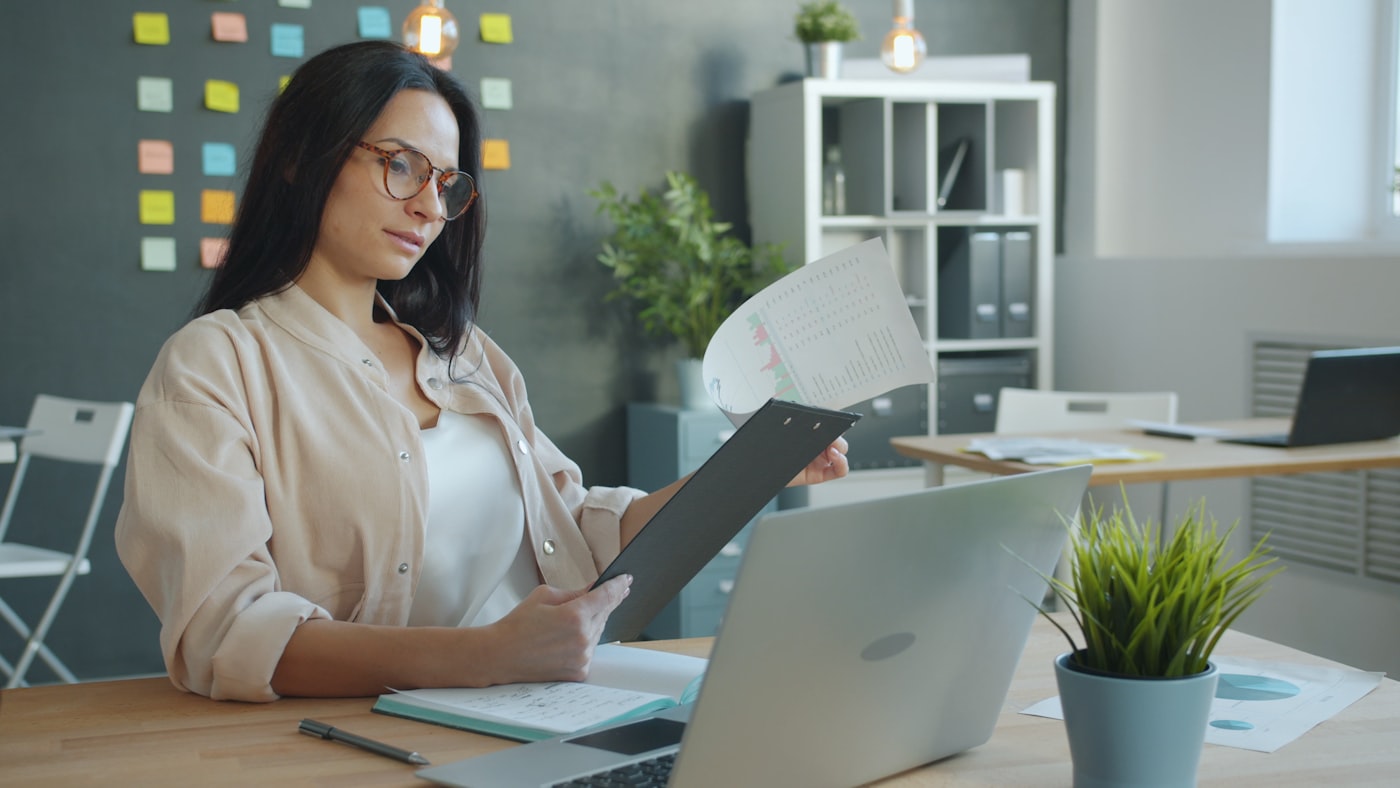 Person reviewing printed pages and documents on an office desk